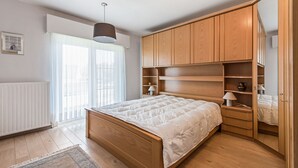 A bedroom with a wooden bed, built-in shelving, and a radiator. - Etoilée GV04 (Koksijde)