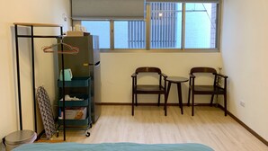 A small, tidy room with a bed, two chairs, a radiator, and a window with blinds. - Good-Days Lovely Suite BRT Calligraphy Greenway (West Dist.)
