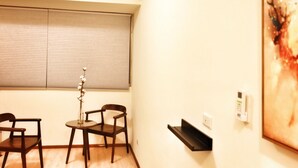 A room with a window, two chairs, a small table, and a wall-mounted shelf. - Good-Days Lovely Suite BRT Calligraphy Greenway (West Dist.)