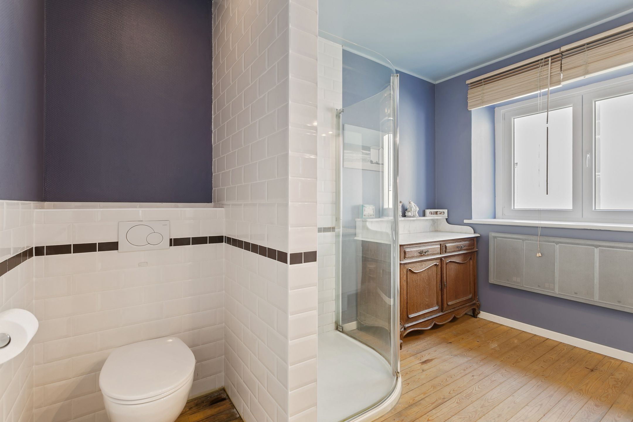 Un baño con inodoro blanco, cabina de ducha de vidrio y tocador con espejo.
