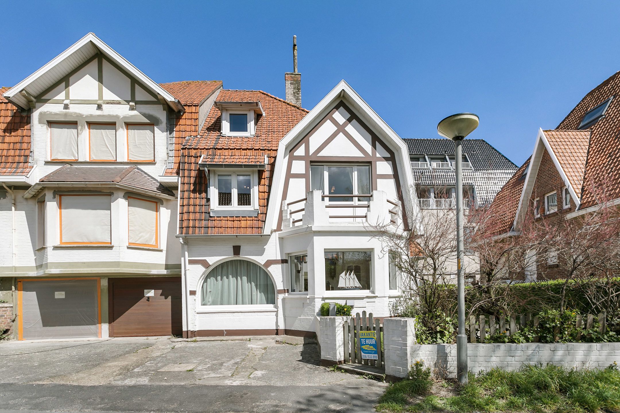 A row of residential houses with distinct architectural styles, including a prominent house with a large bay window and a garage.