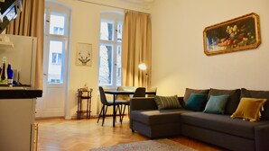 A living room with a sofa, a dining table, and a kitchen area. - Aparthotel Thüringer Hof (Berlin)