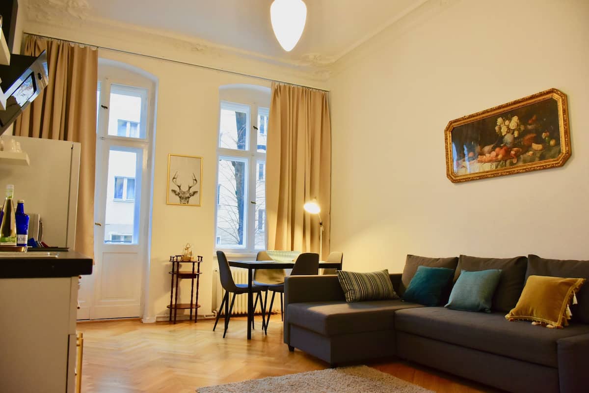 Una sala de estar con sofá, una mesa de comedor y una zona de cocina.