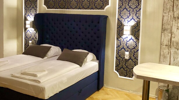 A bedroom with a large bed, a bedside table, and a chair. - Aparthotel Thüringer Hof (Berlin)