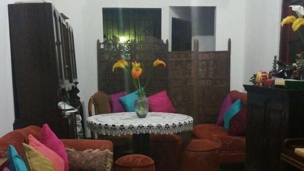 A living room with a red sofa, a small round table with a lace tablecloth, and a patterned floor. - Lindo Apartamento en el Centro de Panama (Panama City)