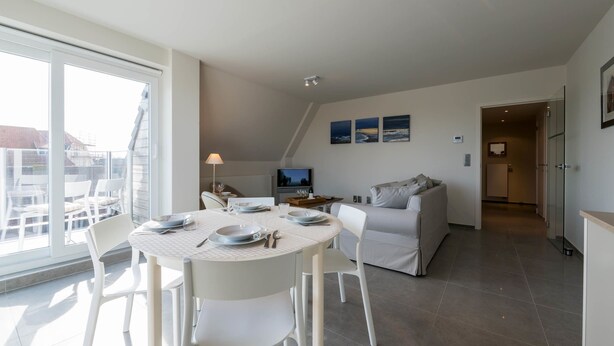 Una cocina moderna con comedor, muebles blancos y un ventanal con vistas a la ciudad.