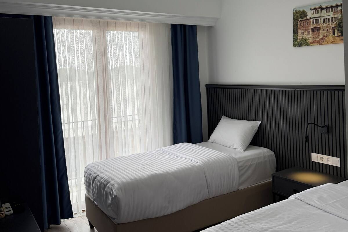 Ett hotellrum med en säng, ett sängbord och en vägglampa.