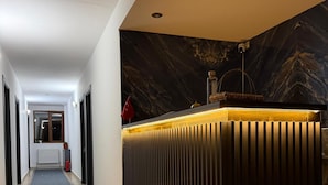 Un espace d’accueil d’hôtel au design moderne, un comptoir de réception, un extincteur et une vue sur le couloir.