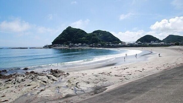A beach with rocky shoreline, clear blue water, and distant green hills. - Hidamari Inn Futama (Kamogawa)