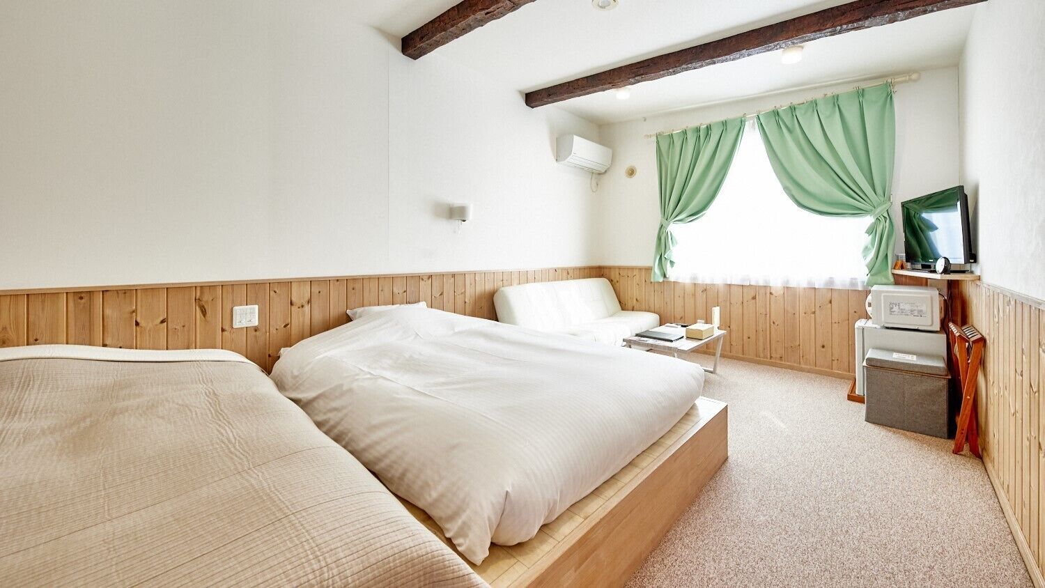 A bedroom with a wooden headboard, a bed with white bedding, a bedside table, a TV, and a window with green curtains.