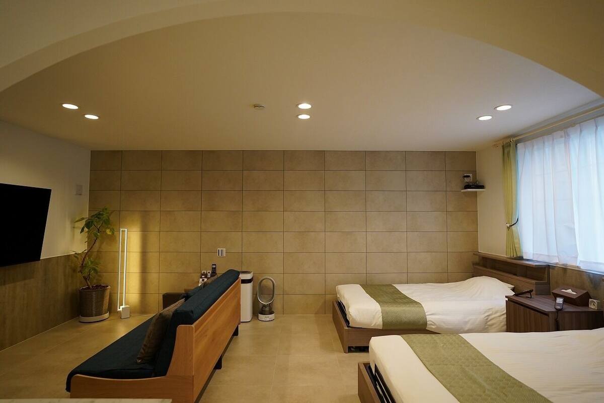 A hotel room with a bed, bedside table, lamp, and a TV mounted on the wall.
