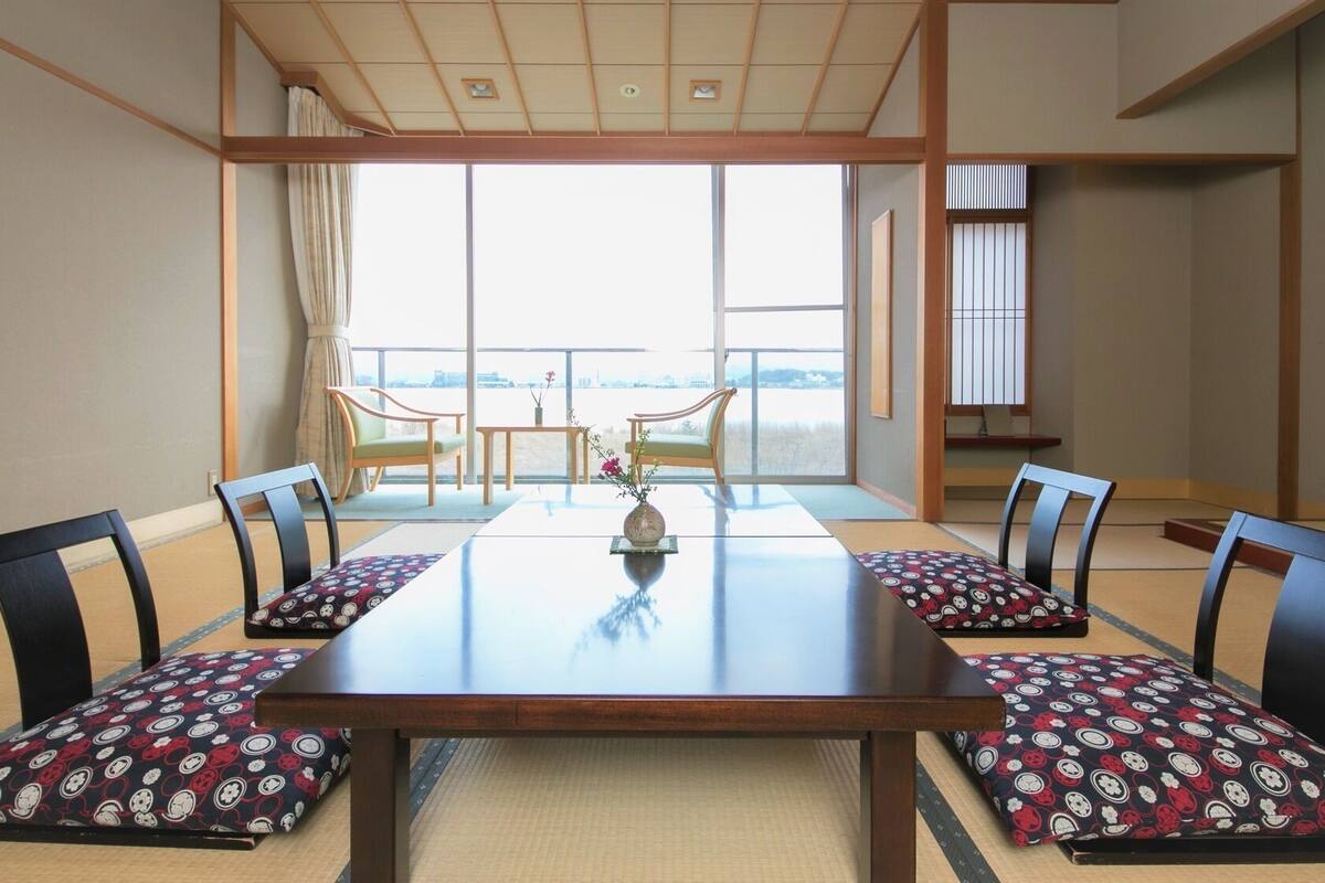 Una habitación japonesa tradicional con suelo de tatami, una mesa baja y puertas correderas shoji.