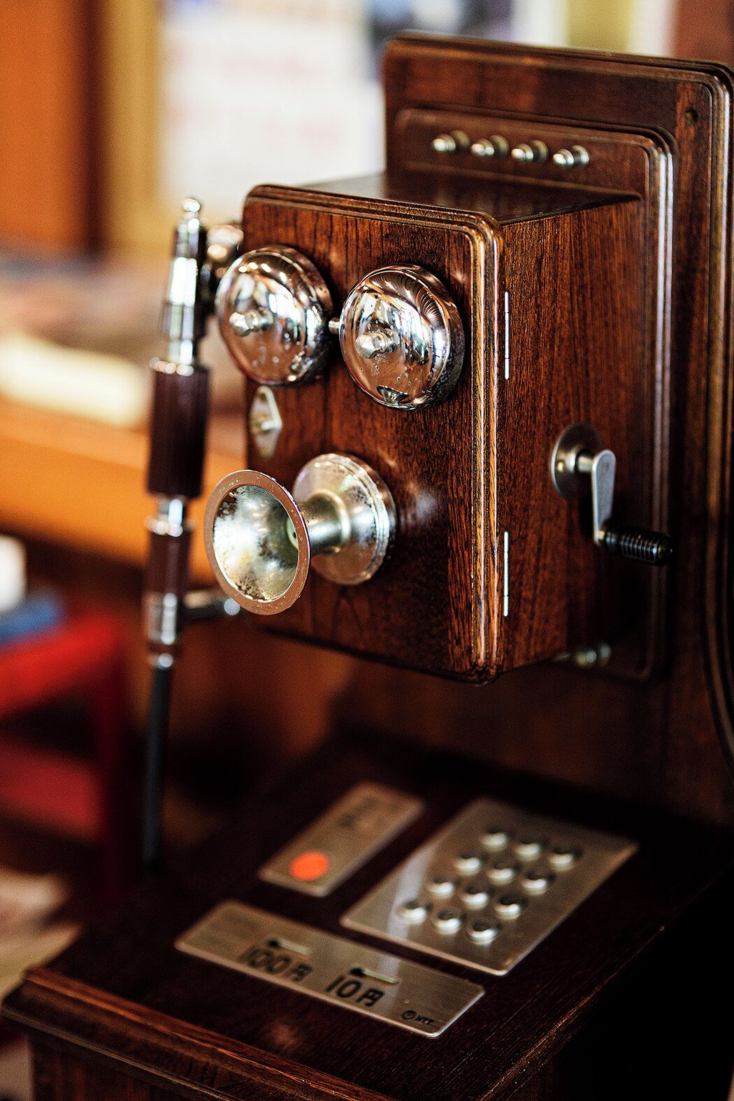 A vintage telephone with a wooden finish and a metal base.