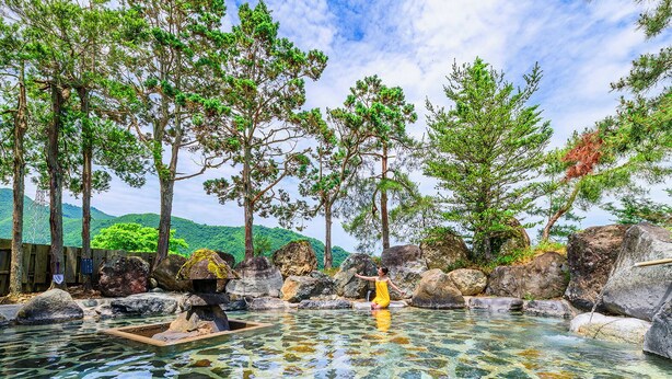 A natural hot spring surrounded by rocks and trees.