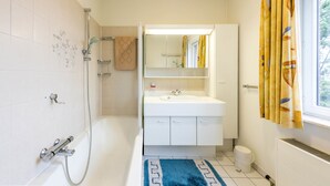 A bathroom with a bathtub, a sink, a mirror, and a shower. - Panisa 401 (Koksijde)