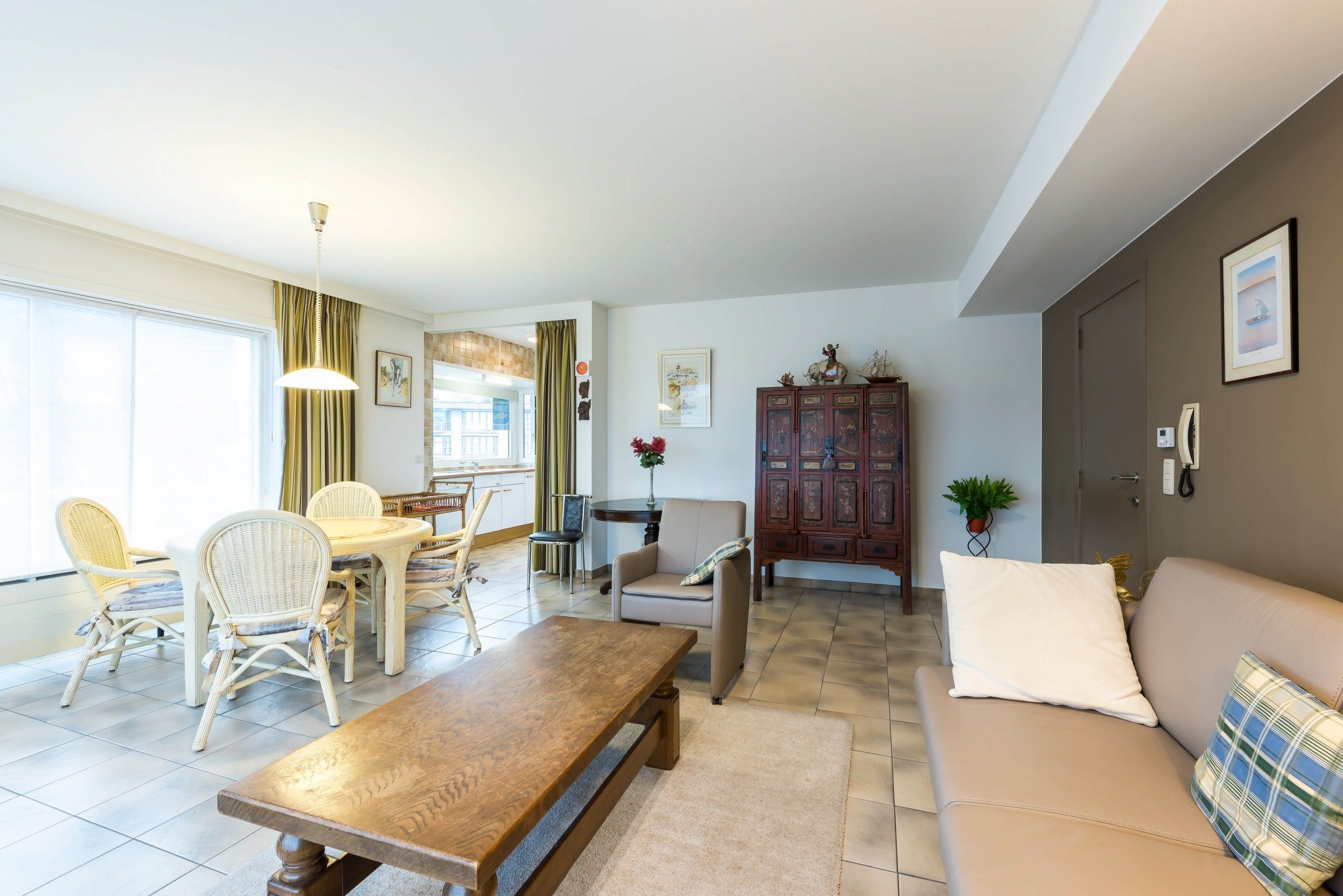 Ein modernes Wohnzimmer mit einem Holzesstisch, einem beigen Sofa und Korbstühlen.