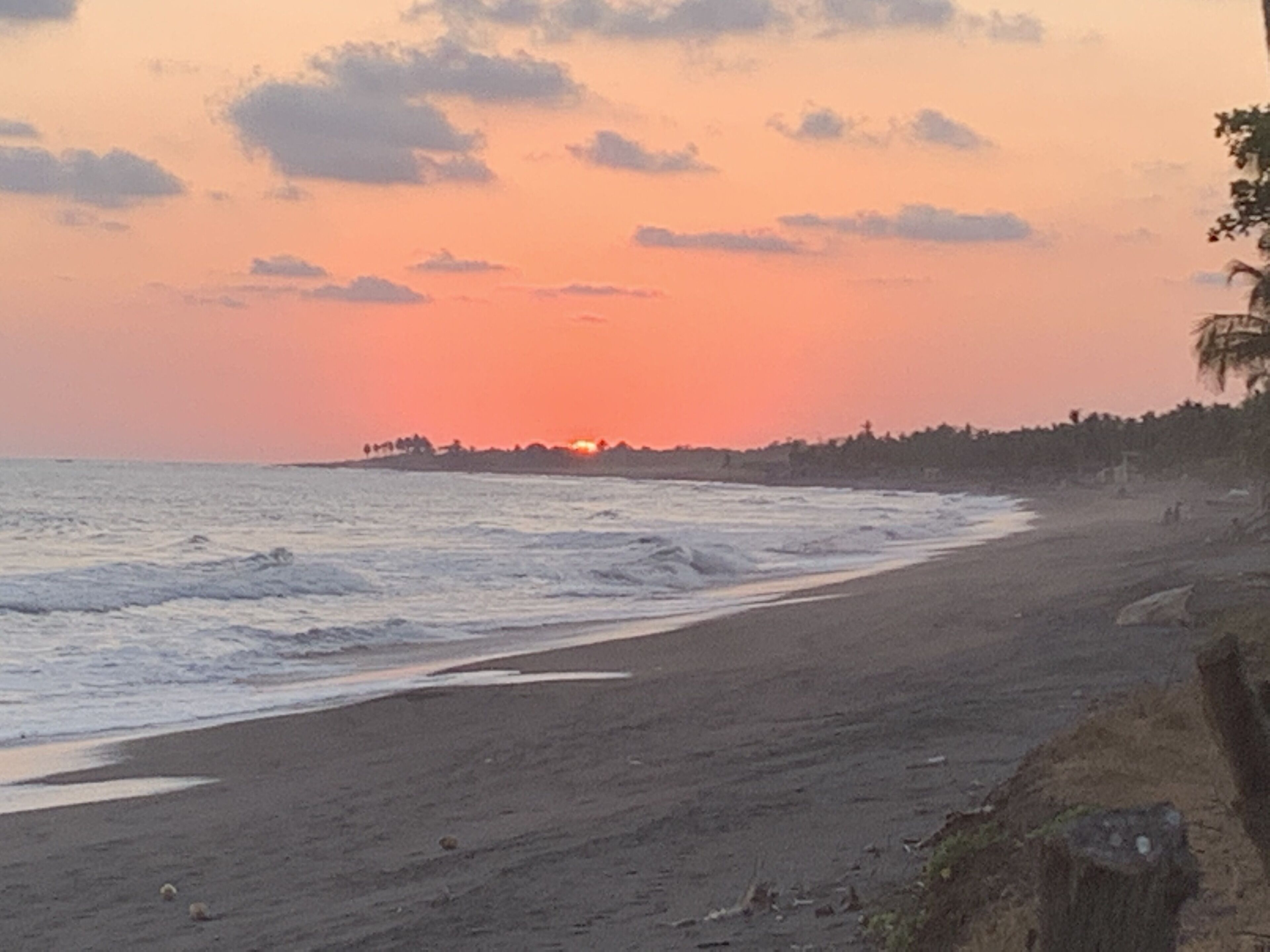 Una playa con un atardecer de fondo.