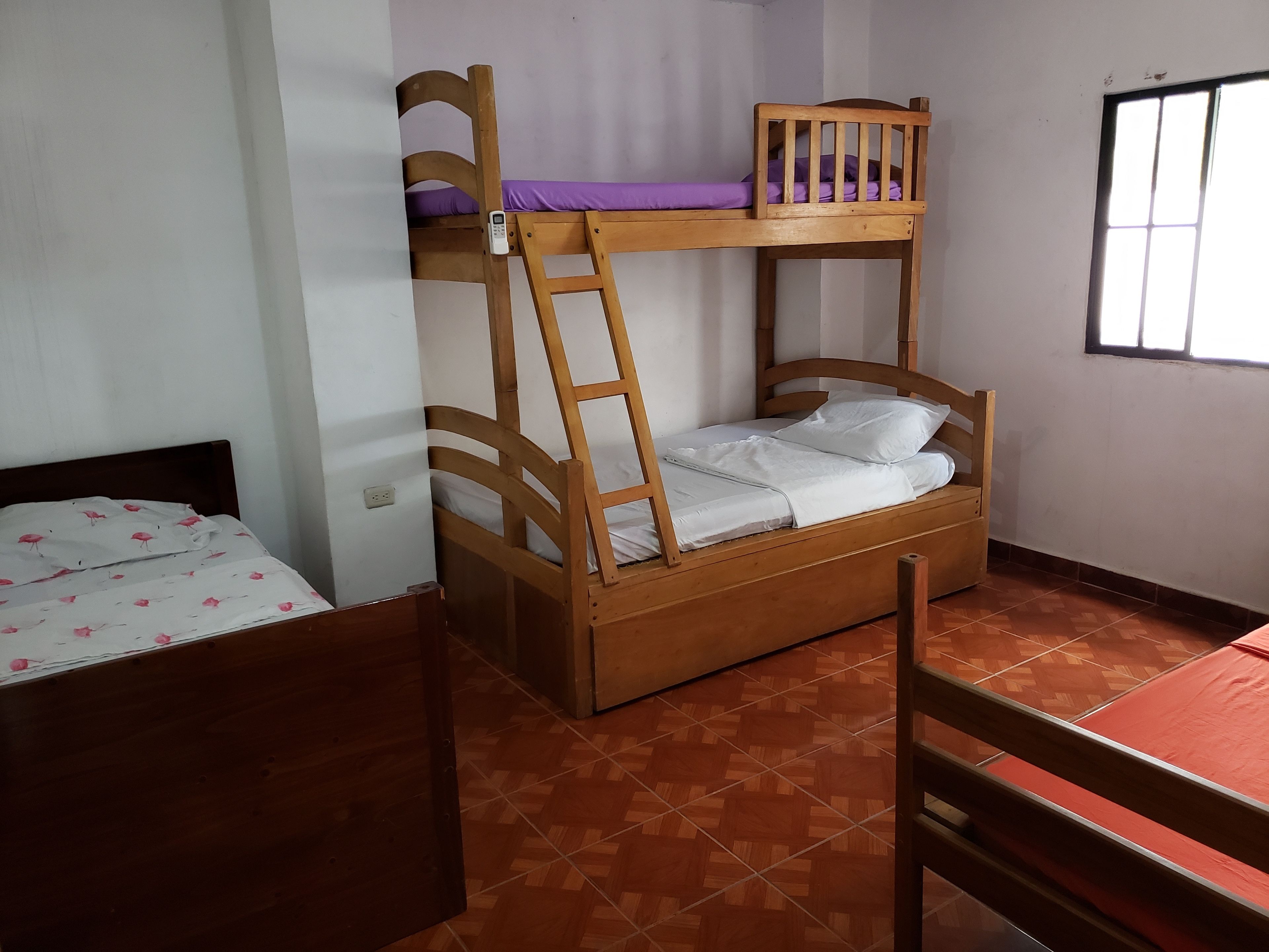 Ein Etagenbett mit einer Leiter, ein unteres Bett mit Blumenmuster und ein Fenster mit Gitterstäben.