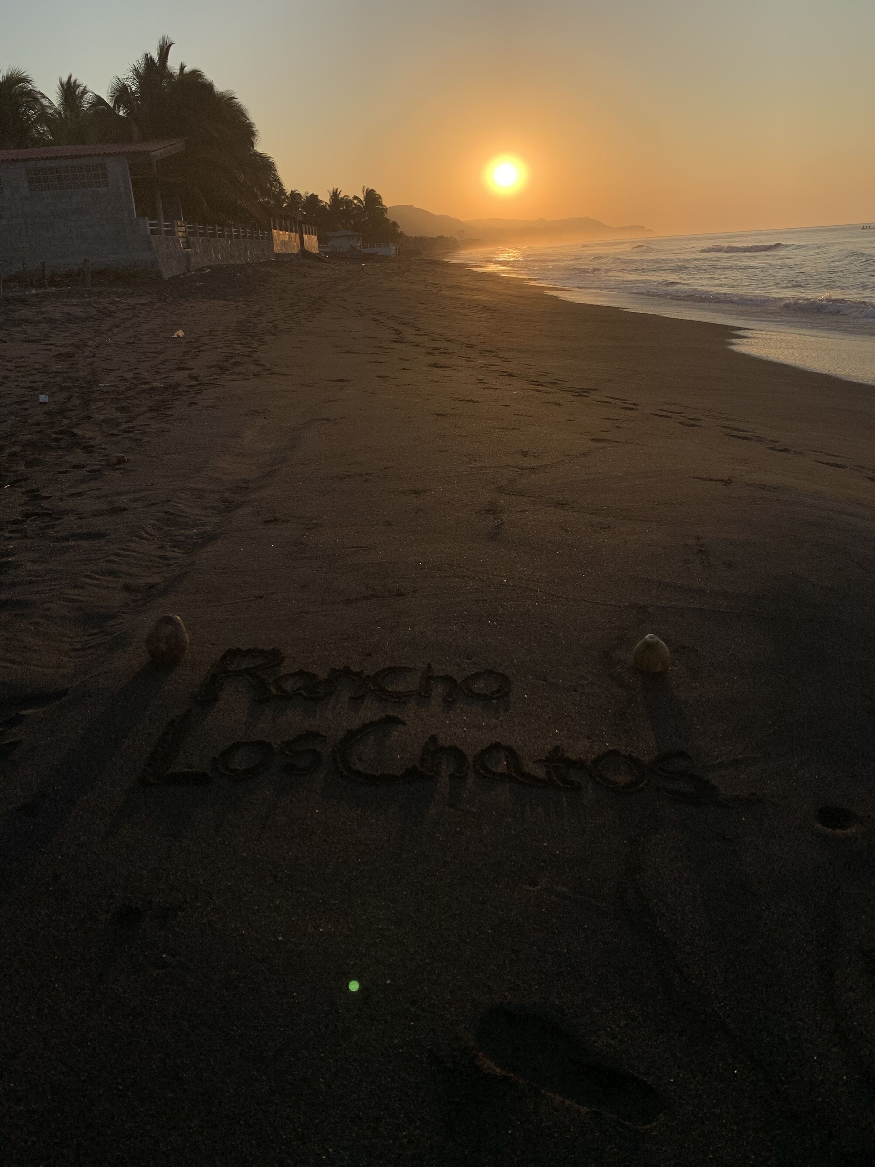 Een strand met voetsporen die 'Rancho Los Chatos' vormen.
