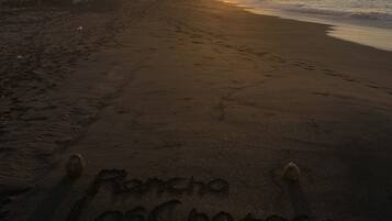 Een strand met voetsporen die 'Rancho Los Chatos' vormen.
