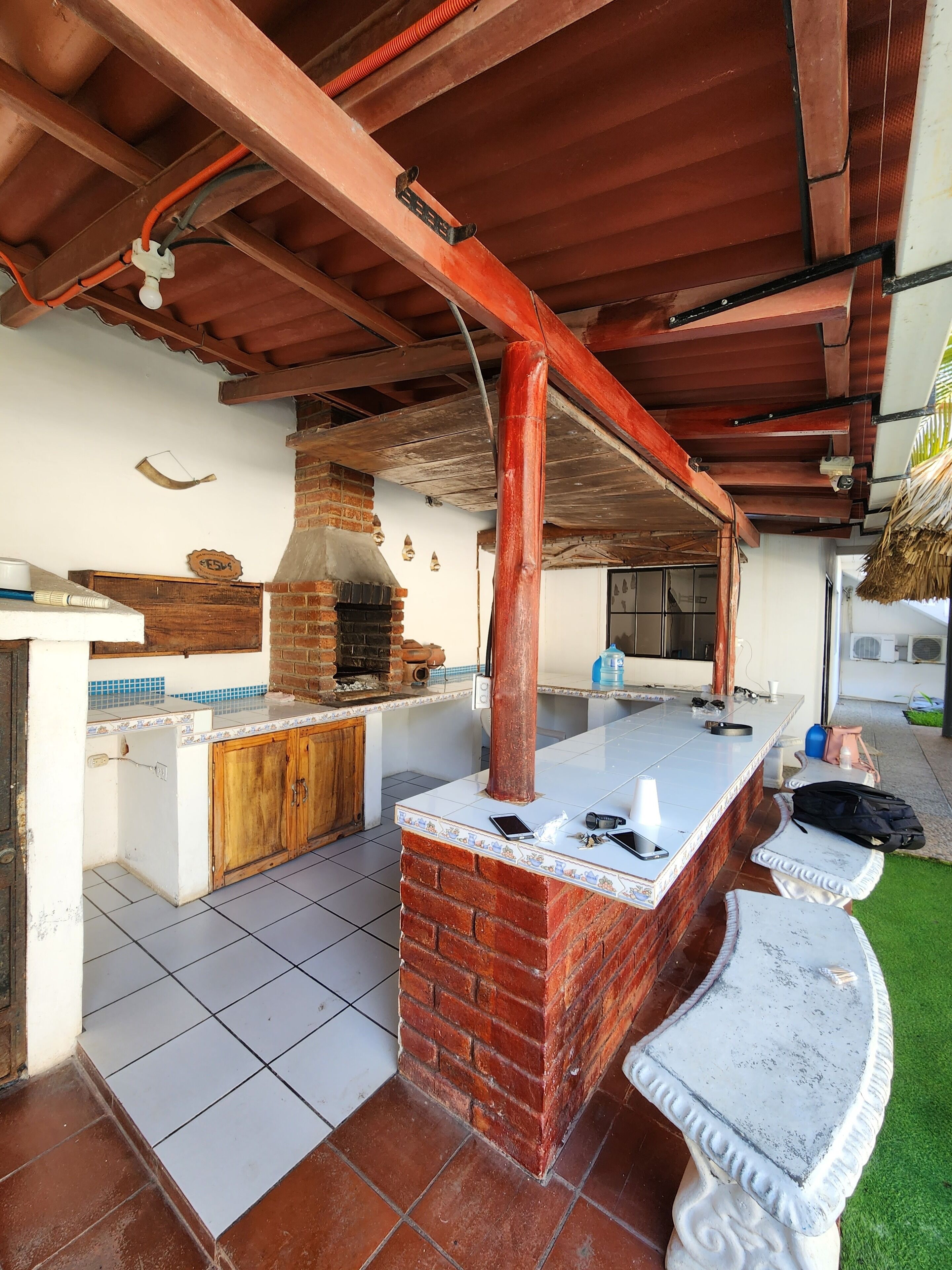 An outdoor kitchen area with a brick oven, wooden cabinets, and tiled flooring.
