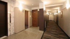 Et hotel med møbelklædt gulv, trædøre og vægmonteret belysning.