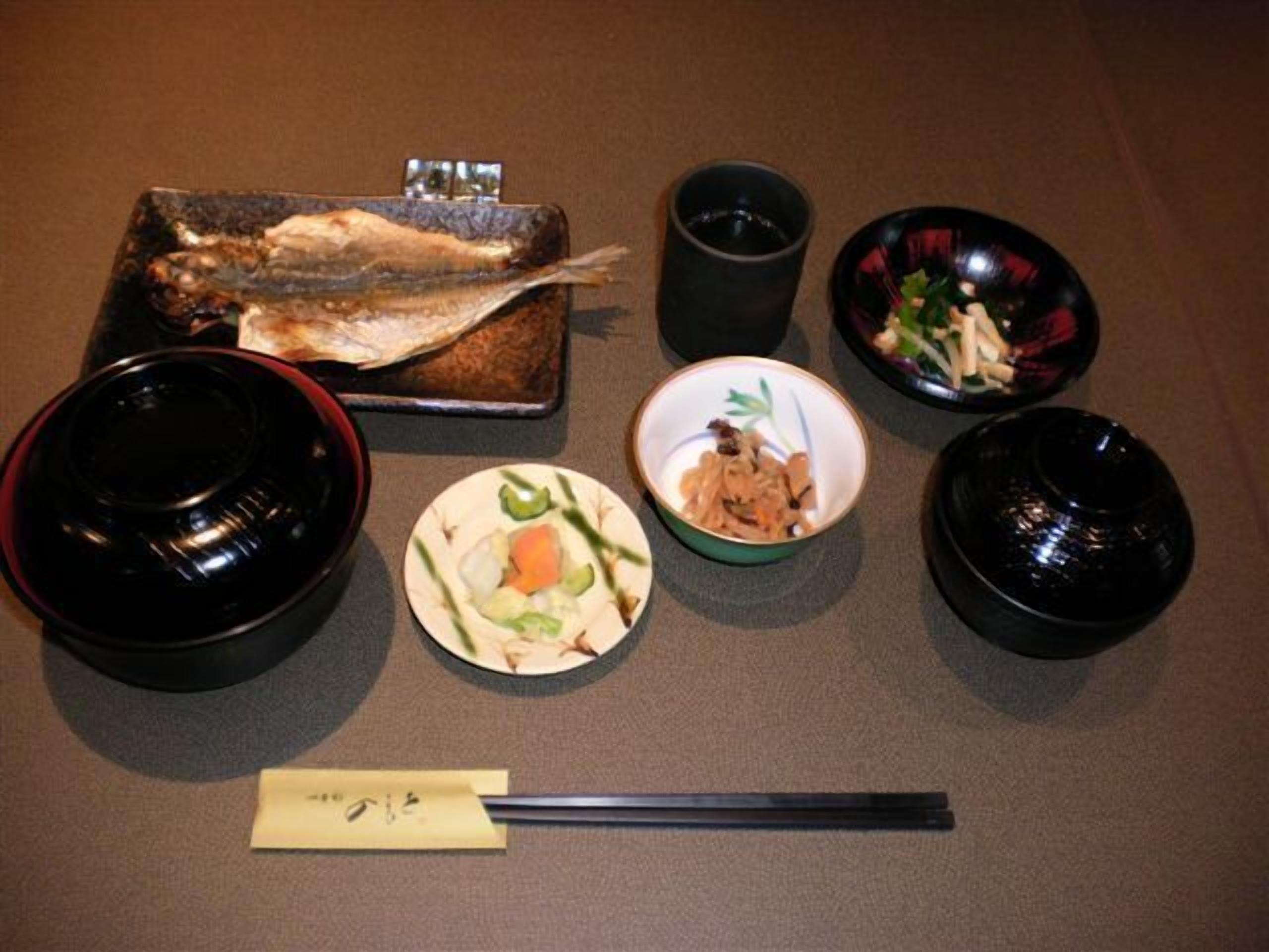 A meal setup with a fish, bowls, and chopsticks on a table.