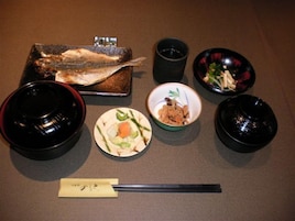 A meal setup with a fish, bowls, and chopsticks on a table.