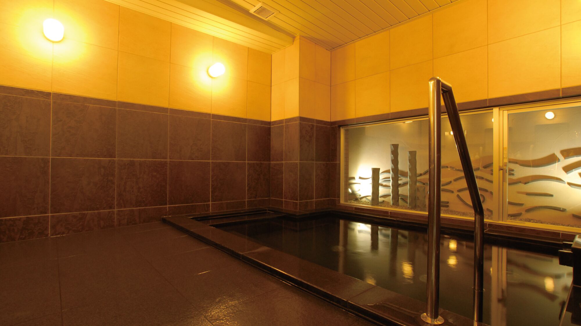A spa room with a hot tub, tiled walls, and a glass partition with a decorative design.