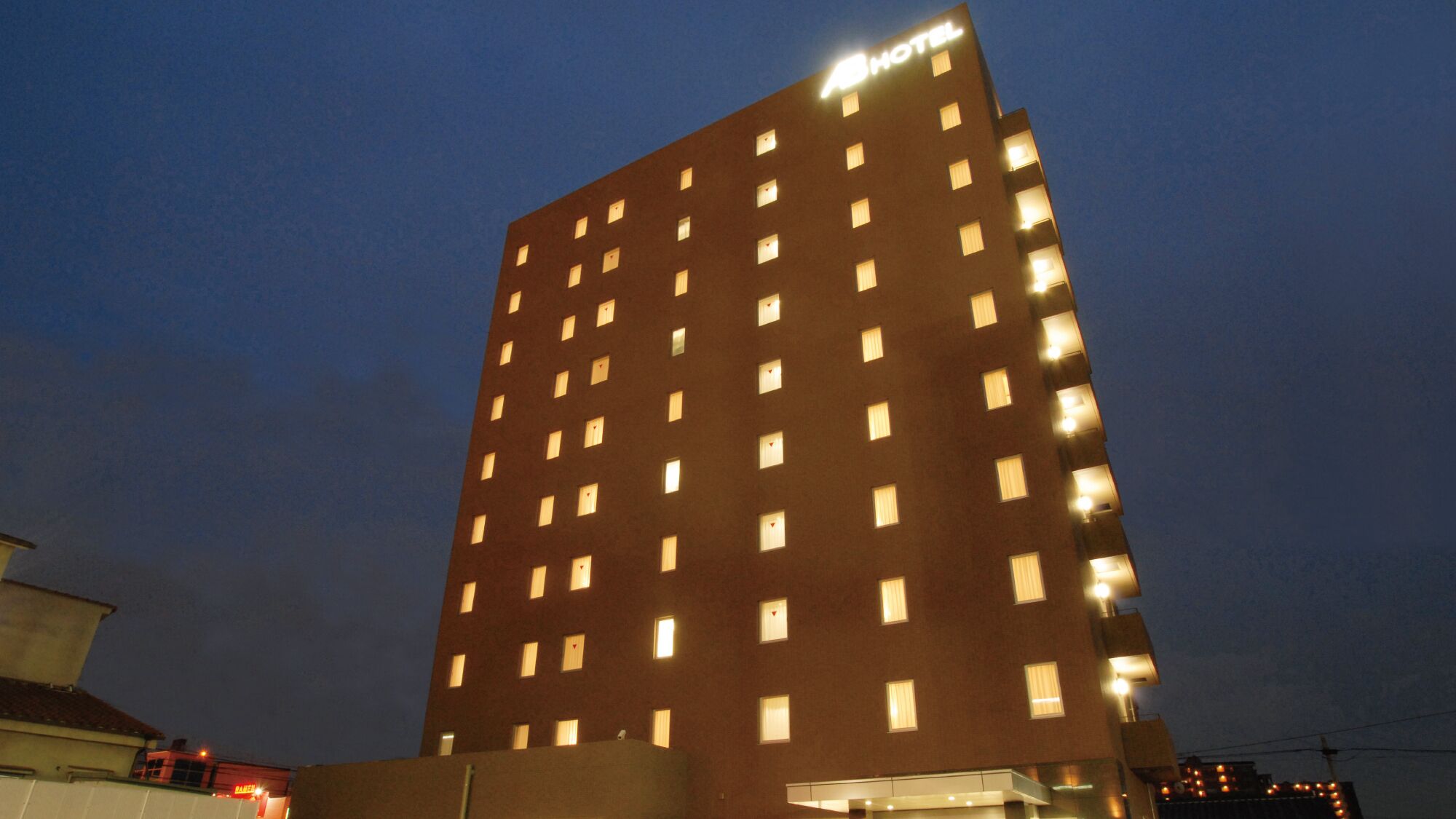 A tall hotel building with multiple illuminated windows and a sign indicating it is a hotel.