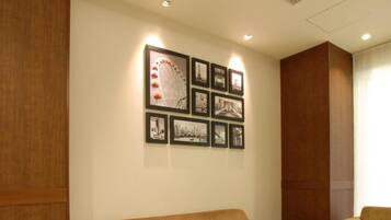 A room with a beige sofa, a small side table, and a wall adorned with framed pictures.