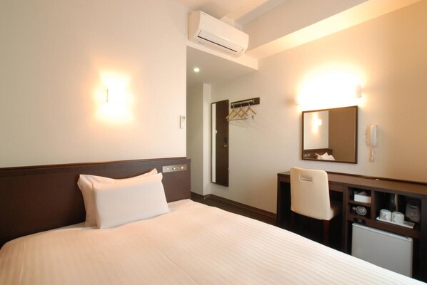 A hotel room with a bed, a desk, a mirror, and an air conditioning unit. - Ab Hotel Komaki (Komaki)