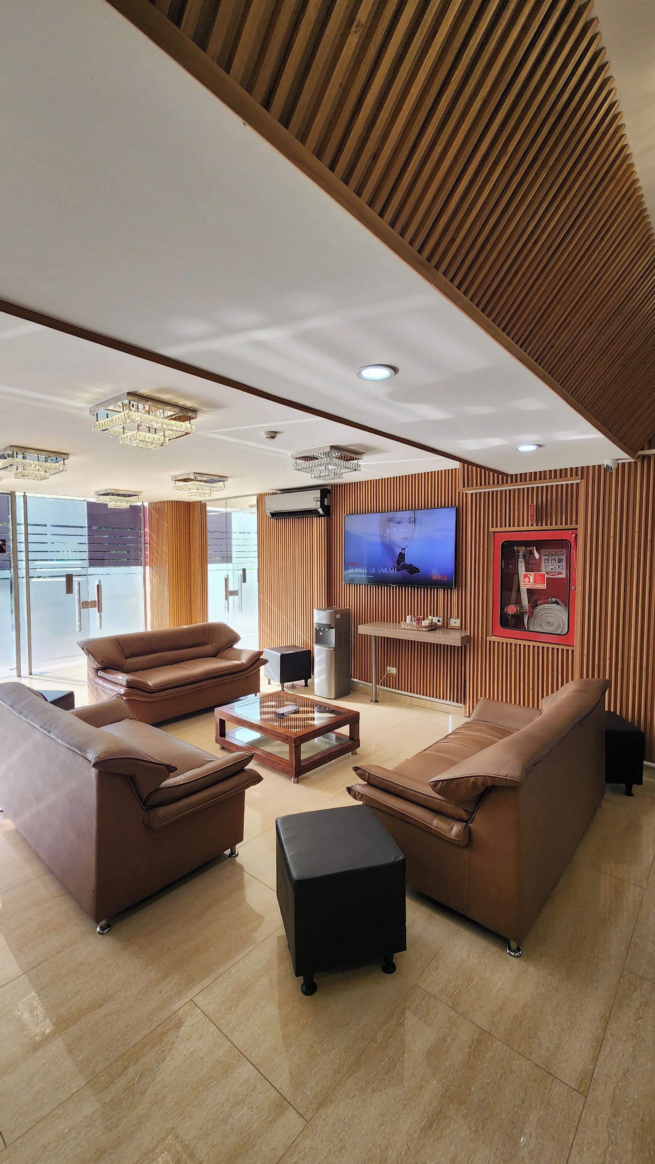 A modern living room with leather sofas, a coffee table, and a flat-screen TV mounted on the wall.
