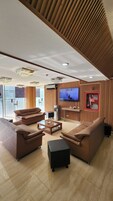 Una sala de estar moderna con sofás de cuero, una mesa de centro y un televisor de pantalla plana montado en la pared.