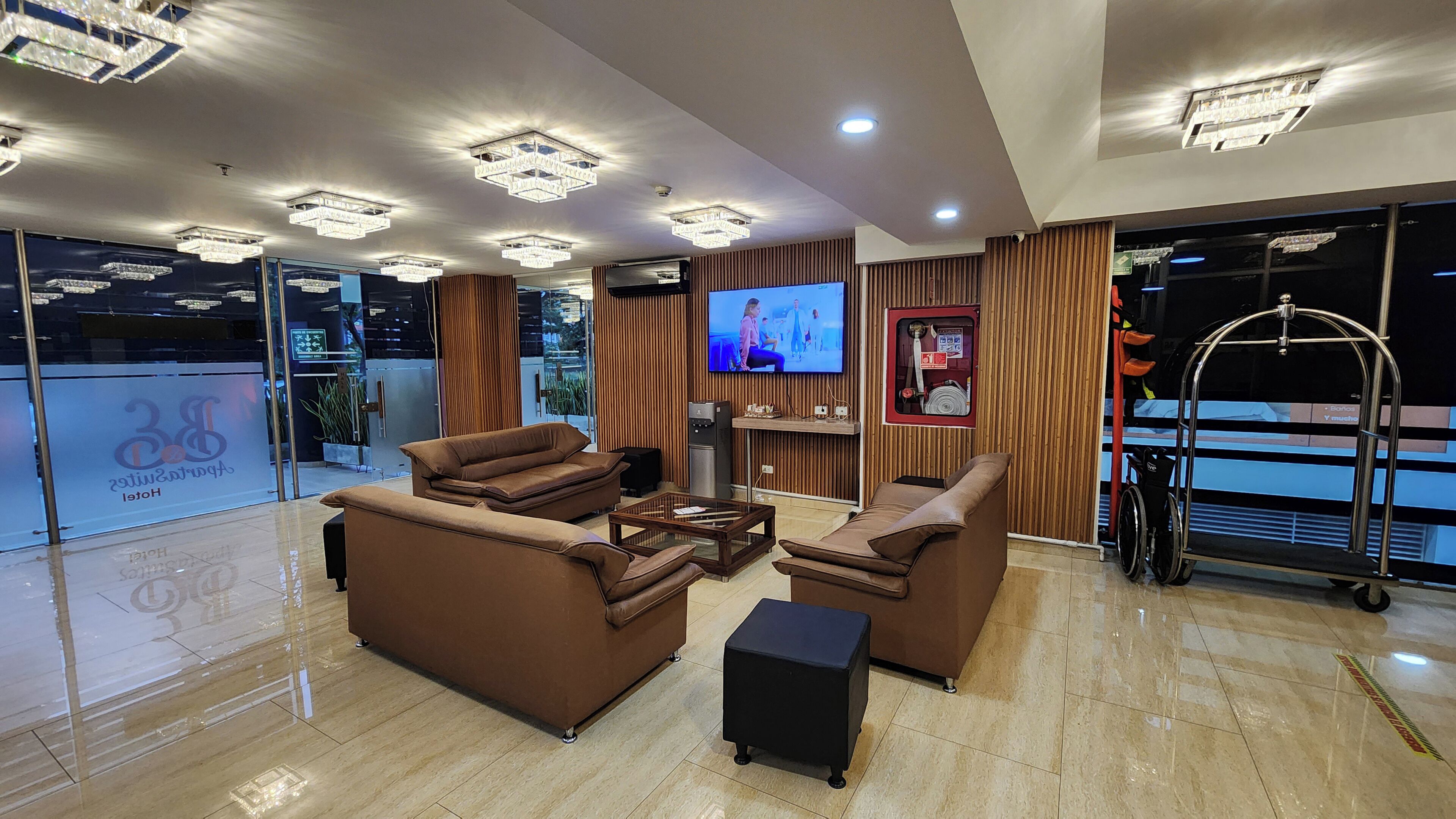 A hotel lobby with a seating area, a television, and a view of the outside.