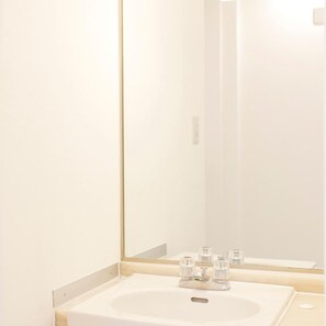 A bathroom with a white sink, a mirror, and a faucet.
