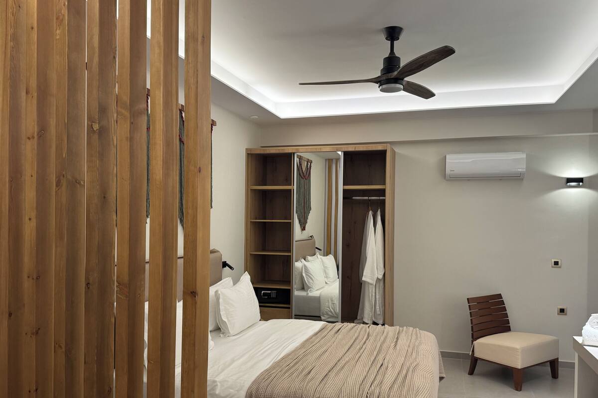 Une chambre à coucher comprenant un lit, une chaise, un bureau, une armoire et un ventilateur de plafond.