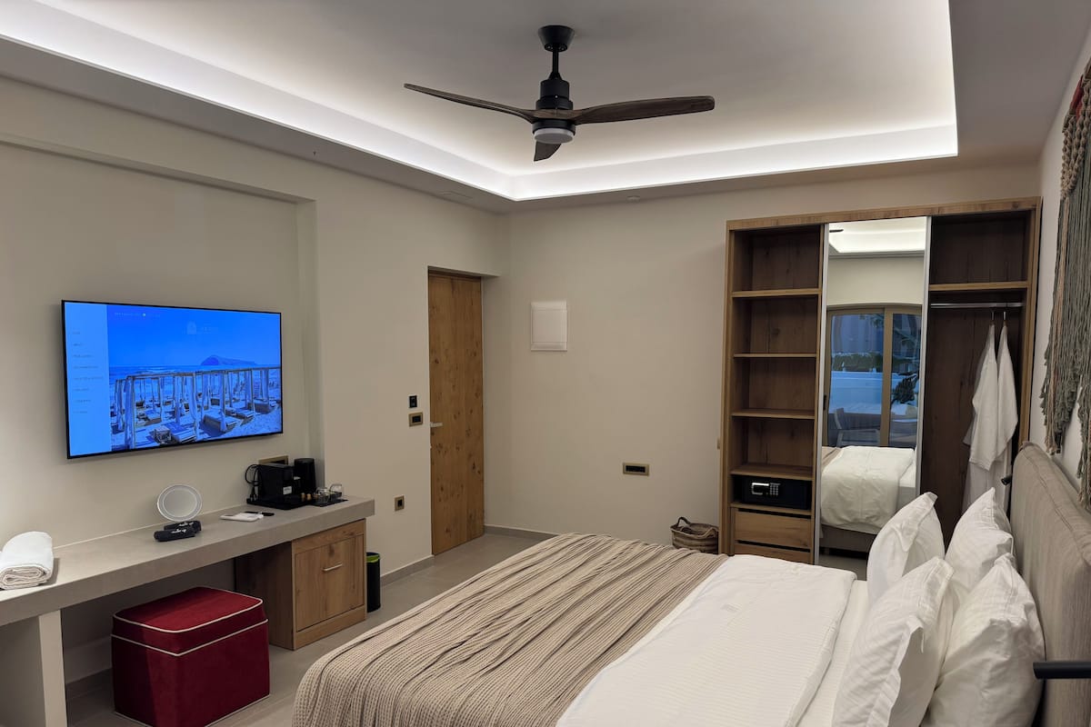 Une chambre moderne équipée d’un lit, d’un bureau, d’une télévision et d’une armoire.