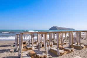 Uma praia com cabanas de madeira e espreguiçadeiras.