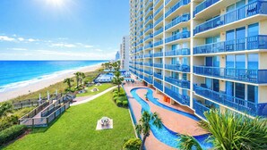 A hotel with a pool, a beach view, and a large building with balconies.