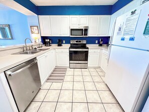 A kitchen with white cabinets, a stainless steel dishwasher, a microwave, and an oven.