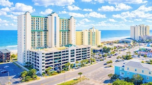 A coastal hotel with multiple floors, a parking garage, and a view of the beach.