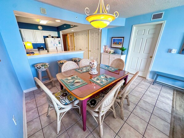 A dining area with a wooden table, wicker chairs, and a chandelier.