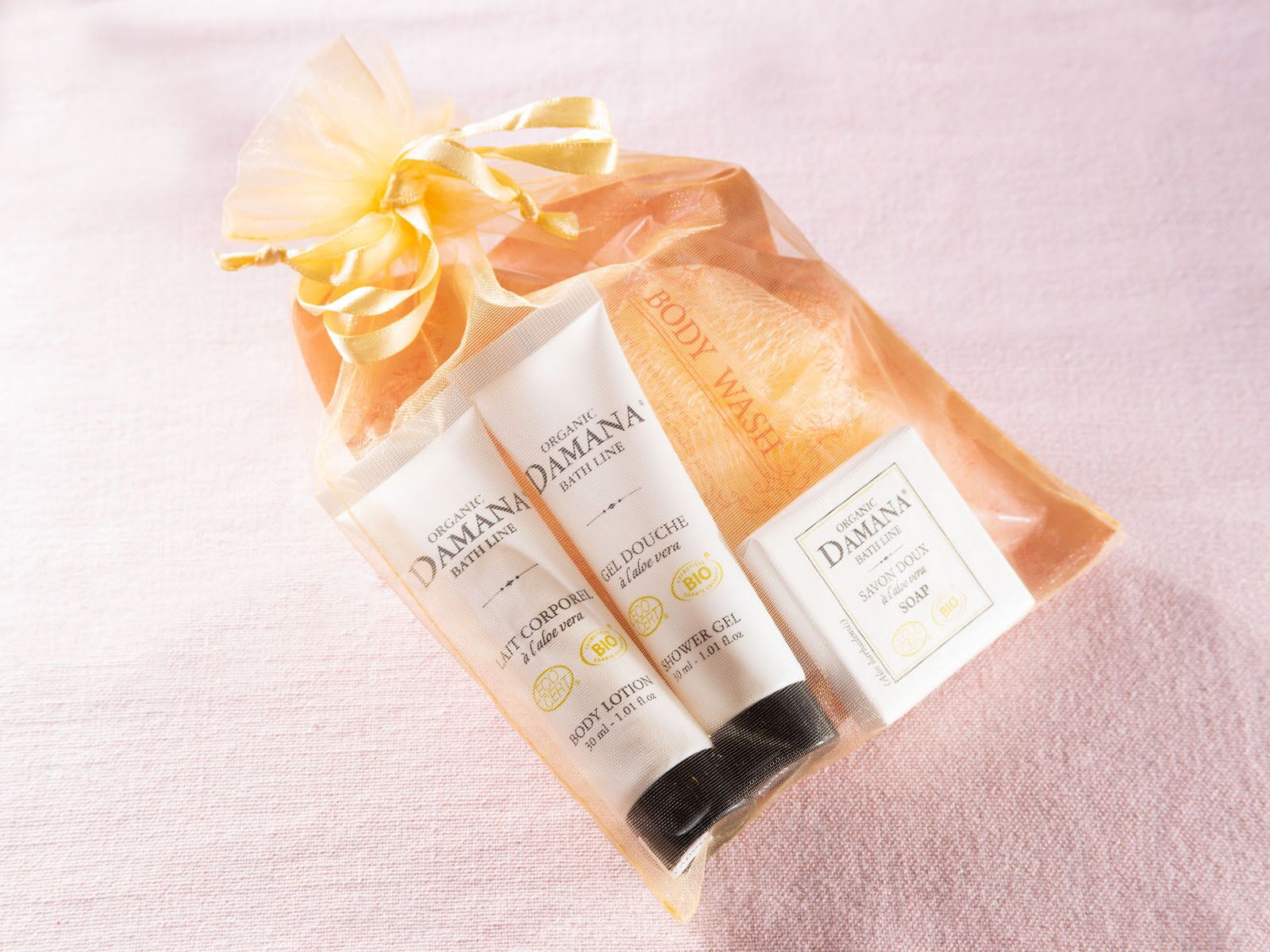 Un sac-cadeau contenant un gel nettoyant pour le corps, un gel douche et une lotion pour le corps, le tout issu de l’agriculture biologique et de la marque Damana.