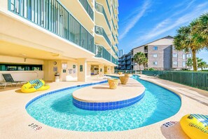 A hotel pool area with a circular pool, lounge chairs, and a palm tree.