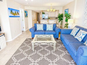 A living room with a blue sofa set, a coffee table, and a patterned rug.