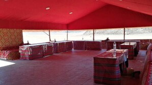 A tented room with cushioned seating and tables, a patterned wall, and a view of a snowy landscape. - Star Walk Camp (Wadi Rum)