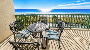 Un balcón con mesa y sillas, con vista a una playa y al océano.