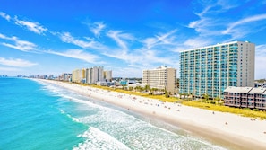 A beachside hotel with multiple high-rise buildings, a sandy beach, and the ocean.