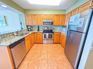 A kitchen with wooden cabinets, a stainless steel refrigerator, a microwave, a stove, and a dishwasher.